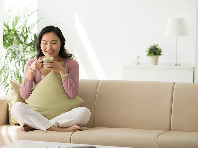 Woman sitting on a couch with a warm drink in a mug